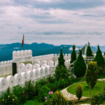 Beautiful landscape of Chail featuring lush green hills, dense pine forests, scenic mountain views, and peaceful surroundings under a clear blue sky.