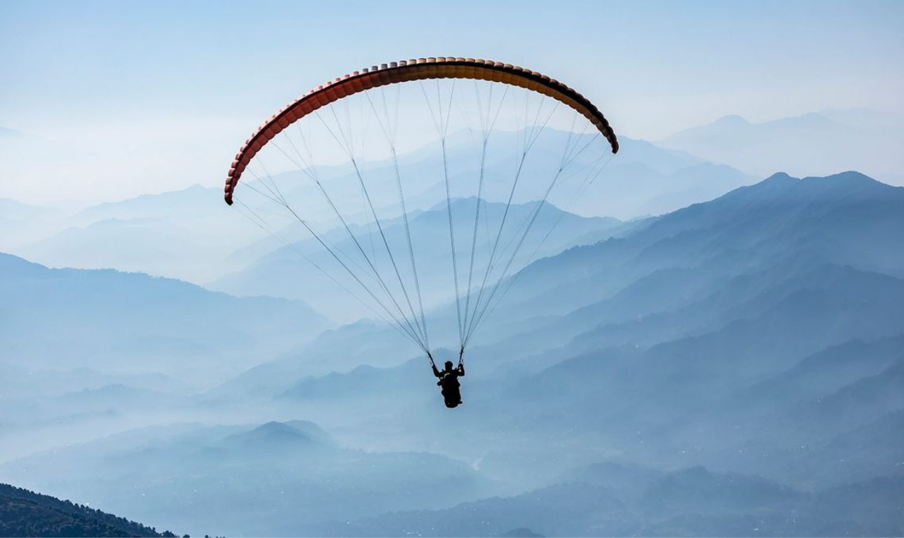 Paragliding adventure over the scenic mountain valleys of Bir Billing with breathtaking views of the Himalayas.