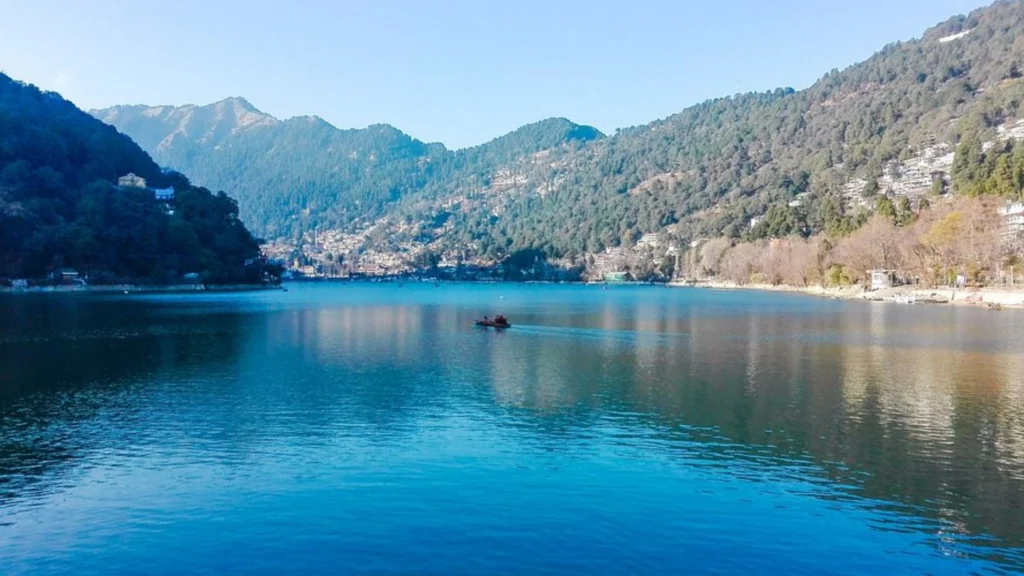 Naini Lake in Nainital surrounded by green hills and colorful boats.