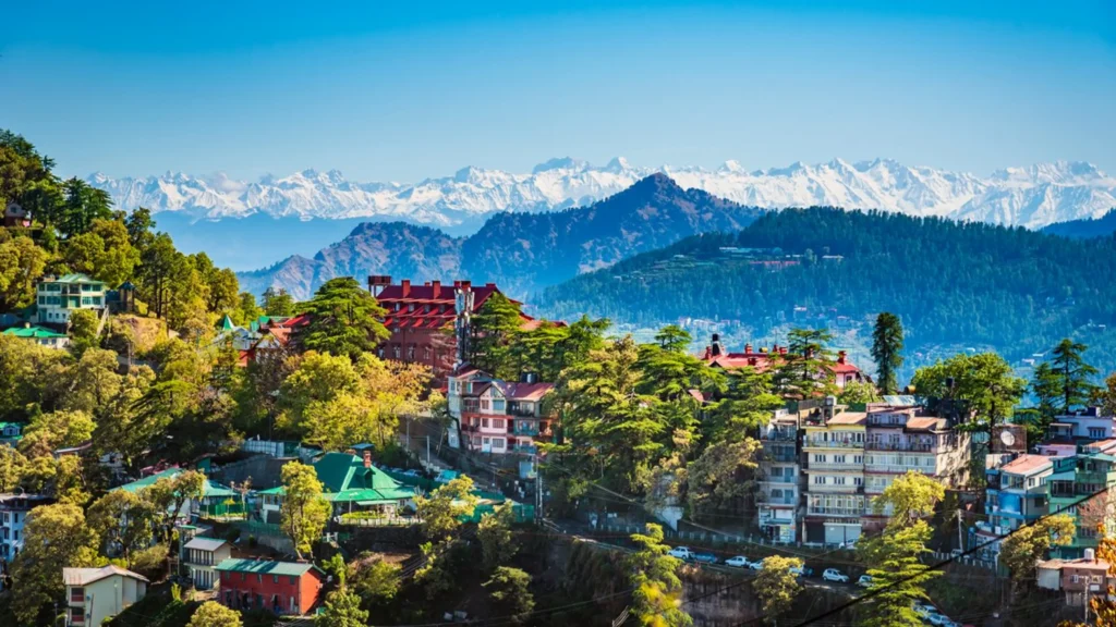 Panoramic view of Shimla with colonial buildings, pine forests, and Himalayan mountains.
